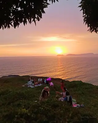 a group of people sitting on a hill watching the sunset at Casa Villa Descanso in Lima