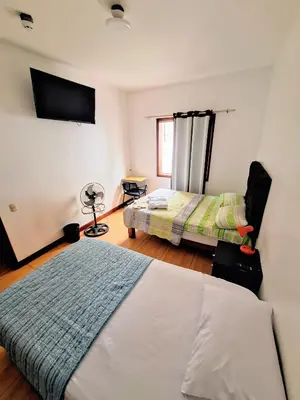 a bedroom with two beds and a tv on the wall at Casa Villa Descanso in Lima