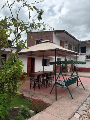 a patio with an umbrella and a table and chairs at hostel arcoiris urubamba in Urubamba