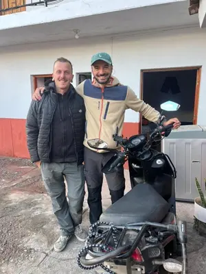 two men are standing next to a motorcycle at hostel arcoiris urubamba in Urubamba