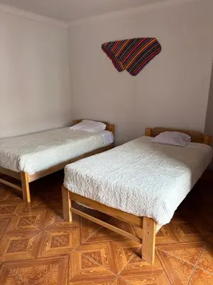 two twin beds in a room with wooden floors at hostel arcoiris urubamba in Urubamba