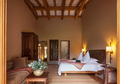 a bedroom with a bed and a couch and a table at Inkaterra Hacienda Urubamba in Urubamba
