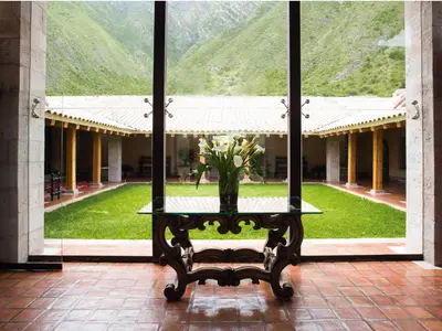 a table with a vase of flowers on it in front of a building at Inkaterra Hacienda Urubamba in Urubamba