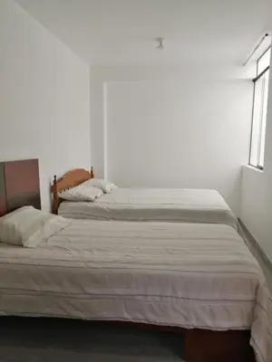 a bedroom with two beds in a white room at Alojamiento Miller in Ayacucho