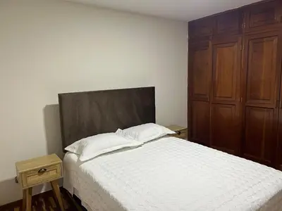 a bedroom with a bed and a wooden cabinet at Apartment - US Embassy in Lima