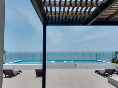 a swimming pool with a view of the beach at Panoramic Elegante departamento in Lima