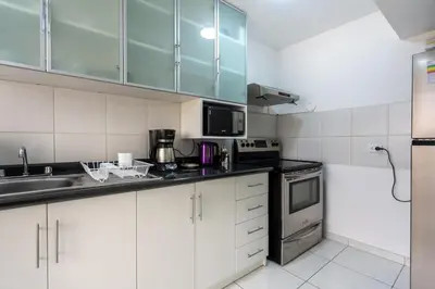 a kitchen with white cabinets and a sink at Basílica 3BR by Geko in Lima