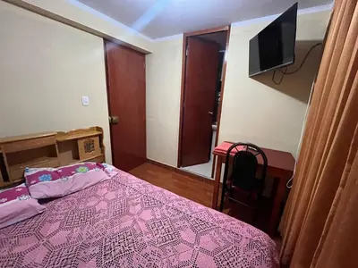 a bedroom with a pink bed and a television at Habitación con baño privado in Ayacucho
