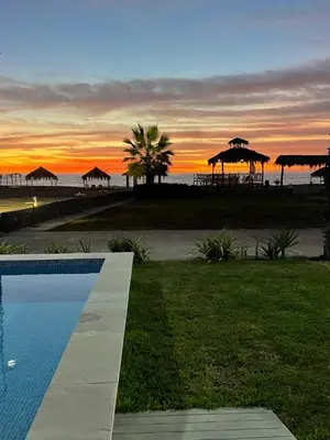 a swimming pool with a view of the beach at sunset at Casa de playa en Chincha Baja in Chincha Baja