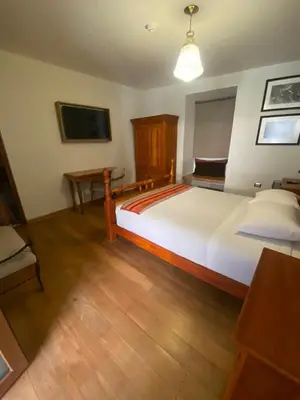 a bedroom with a large white bed and a desk at Artinka Boutique Hotel in Cusco