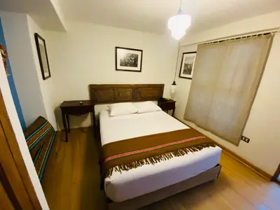 a bedroom with a bed and a table and a window at Artinka Boutique Hotel in Cusco
