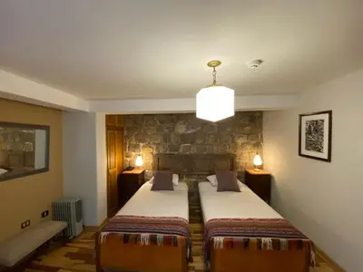 a bedroom with a bed and a stone wall at Artinka Boutique Hotel in Cusco