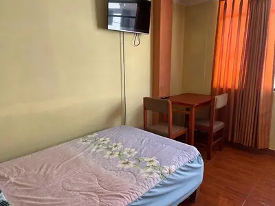 a room with a bed and a table with a television at Habitación 2 camas y baño privado in Ayacucho