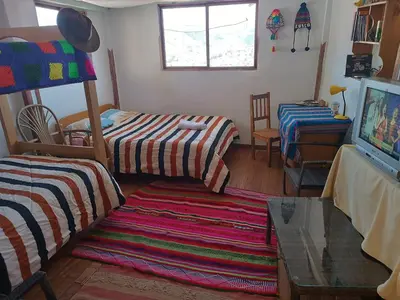 a room with two beds and a table and a tv at Sanblas House in Cusco