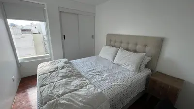 a bed with white sheets and pillows in a bedroom at Brand new modern apartment in Lima