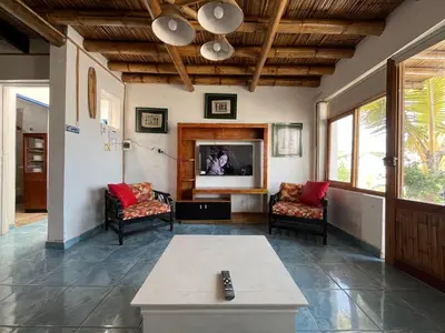 a living room with two chairs and a flat screen tv at Playa El Silencio House Facing the Sea in Bombiso
