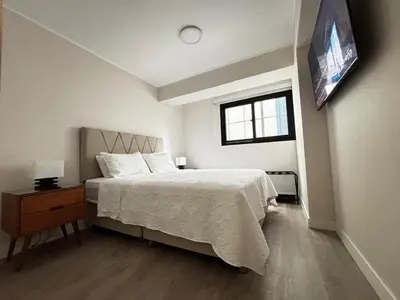 a white bedroom with a bed and a window at Apartamento en Miraflores in Lima