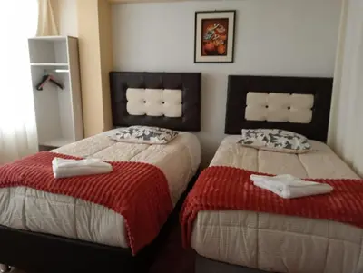 a bedroom with two beds with red and white blankets at Apartamento familiar 9 personas tranporte incluido in Cusco