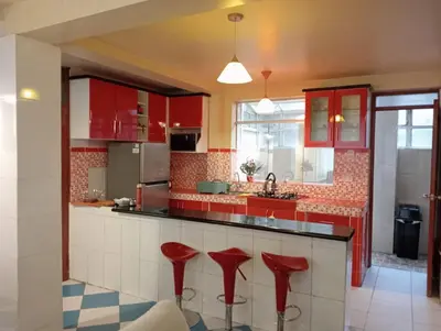a kitchen with red cabinets and red stools at Apartamento familiar 9 personas tranporte incluido in Cusco
