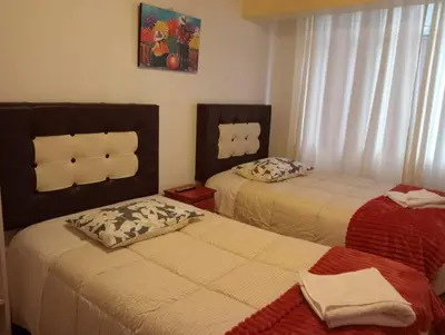 a bedroom with two beds and a window at Apartamento familiar 9 personas tranporte incluido in Cusco