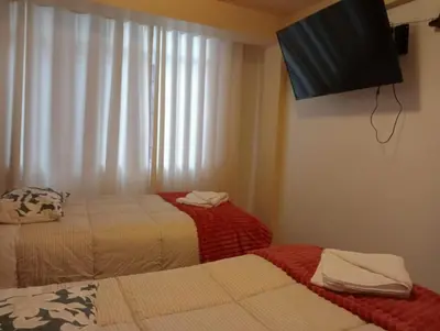 a room with two beds and a flat screen tv at Apartamento familiar 9 personas tranporte incluido in Cusco