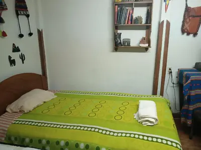 a small bed in a room with a green blanket at San Blas House in Cusco