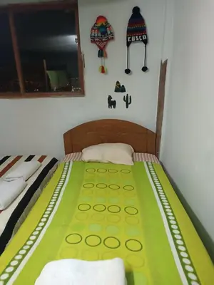 a bedroom with a bed with a green and yellow blanket at San Blas House in Cusco