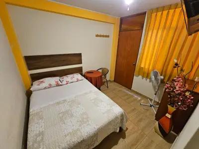 a bedroom with a bed and a desk with a fan at Hospedaje Valencia in Ica