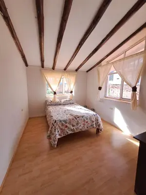 a bedroom with a bed and two windows at The yellow house in the valley in Urubamba