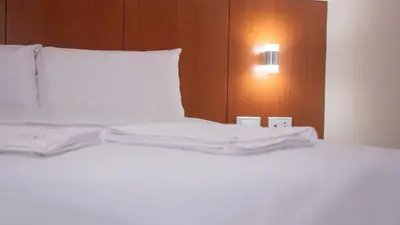 a bed with white sheets and a white pillow at Hotel Centro Huancayo in Huancayo