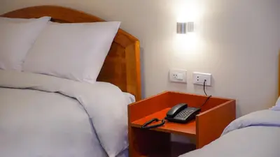a bedroom with a bed and a phone on a night stand at Hotel Centro Huancayo in Huancayo