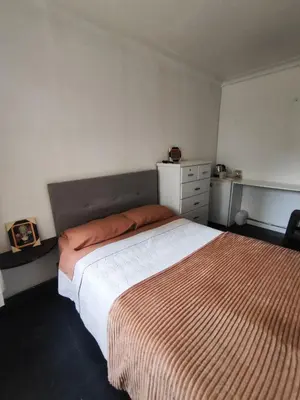 a bedroom with a bed with a orange and white blanket at Habitación acogedora cerca a Larcomar in Lima