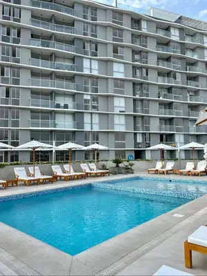 a swimming pool with chairs and a large building at Come and have fun with the family in San Bartolo