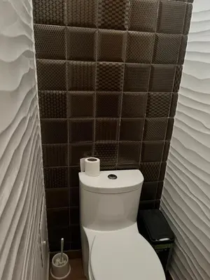 a bathroom with a toilet and a black tiled wall at Sunny refuge with large gardens in Cieneguilla