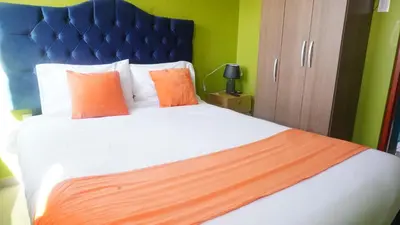 a bedroom with a large bed with orange pillows at BR Comfortable Stay Inn in Cusco