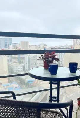 a table with two cups and a potted plant on a window at Duplex con piscina en Miraflores in Lima