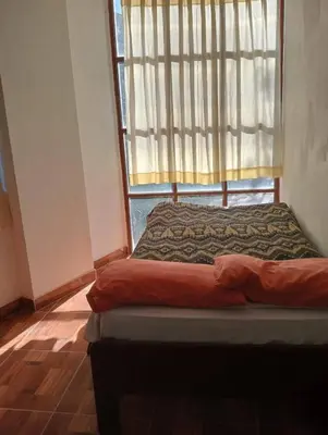 a bed sitting in a room with a window at Hostal Aylluq Wasin - Guest House-Casa de Familia in Urubamba