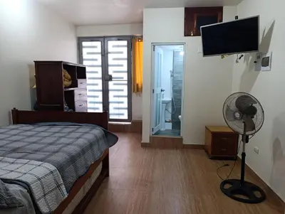 a bedroom with a bed and a fan and a television at Casa Hospedaje Terraza con vista a La Merced in La Merced