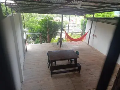 a porch with a hammock and a table on it at Casa Hospedaje Terraza con vista a La Merced in La Merced