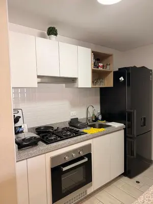 a kitchen with white cabinets and a stove and a refrigerator at Relajar y trabajar en Miraflores in Lima