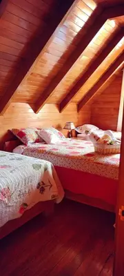 a bedroom with two beds in a wooden attic at La Cabaña de Mary in Oxapampa