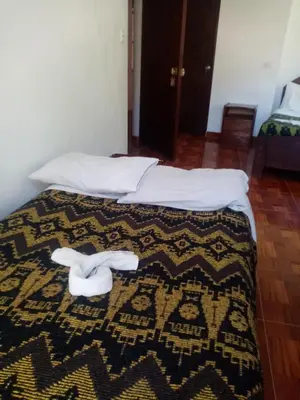 a bedroom with two beds with white sheets and white shoes at Hostal Aylluq Wasin - Guest House-Casa de Familia in Urubamba