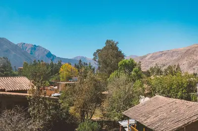 a view of a village with mountains in the background at Hostal Aylluq Wasin - Guest House-Casa de Familia in Urubamba