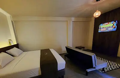 a bedroom with a bed and a chair and a tv at China Chancay Hotel in Chancay