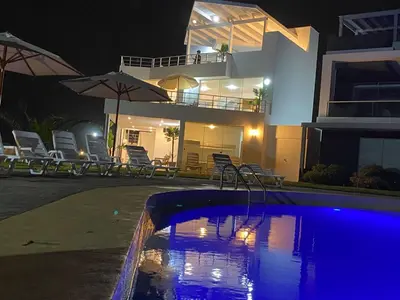 a swimming pool in front of a house at night at Casa de Playa con vista panorámica in Islote Los Leones