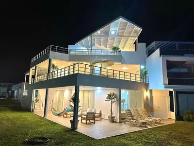 a large white house with a balcony at night at Casa de Playa con vista panorámica in Islote Los Leones
