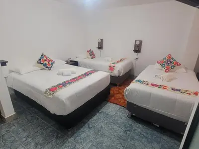 a room with three beds in a room at Oasis Inka Machupicchu in Machu Picchu