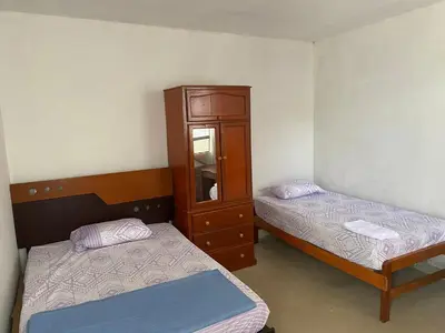 two beds in a room with a cabinet and two beds at Casa de campo en Chincha in Chincha