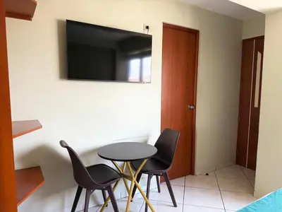 a table and chairs with a television on a wall at Hotel Limamar in Lima
