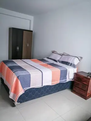a bedroom with a bed and a wooden cabinet at Amplio departamento completo cerca al aeropuerto in Lima